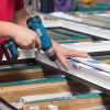 Operario instalando ventana de aluminio en taller de carpintería aluminio en Málaga con herramientas profesionales.